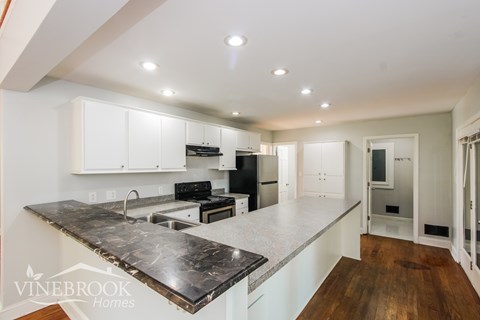 A kitchen with a marble countertop and white cabinets.