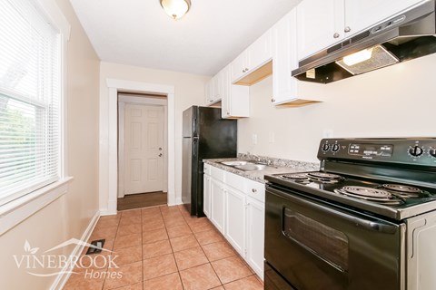 A kitchen with a black refrigerator and a black stove top oven.