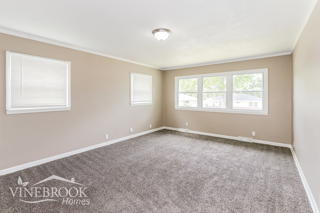 the living room of a home with carpet and two windows