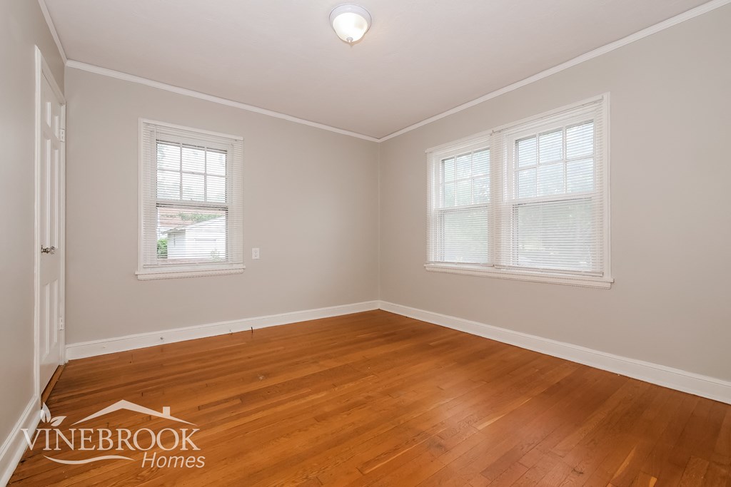 the living room of a home with wood floors and two windows
