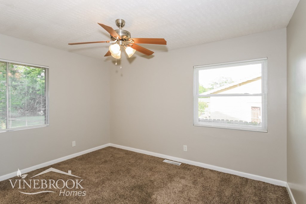 a living room with carpet and a ceiling fan