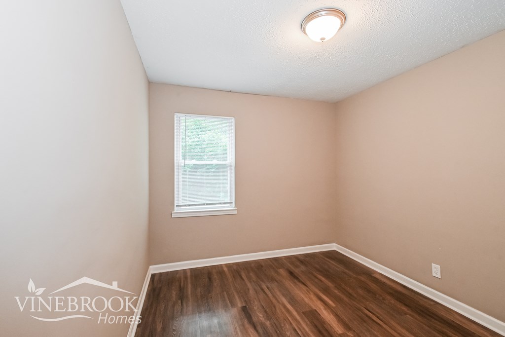 the upstairs bedroom with hardwood flooring and a window