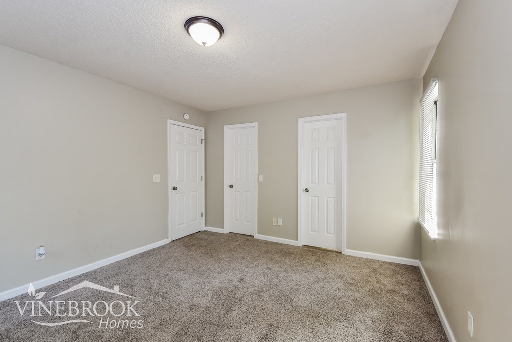 an empty living room with two doors and a carpeted floor