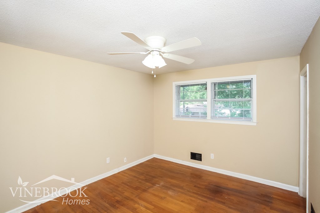 a bedroom with hardwood flooring and a ceiling fan