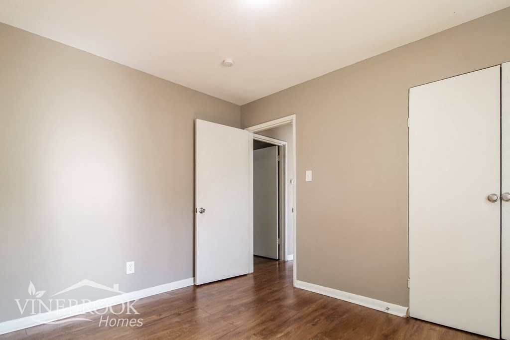 a bedroom with white walls and a door to a closet