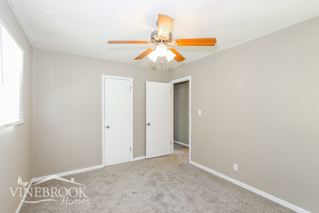 a bedroom with a ceiling fan and a door to a closet
