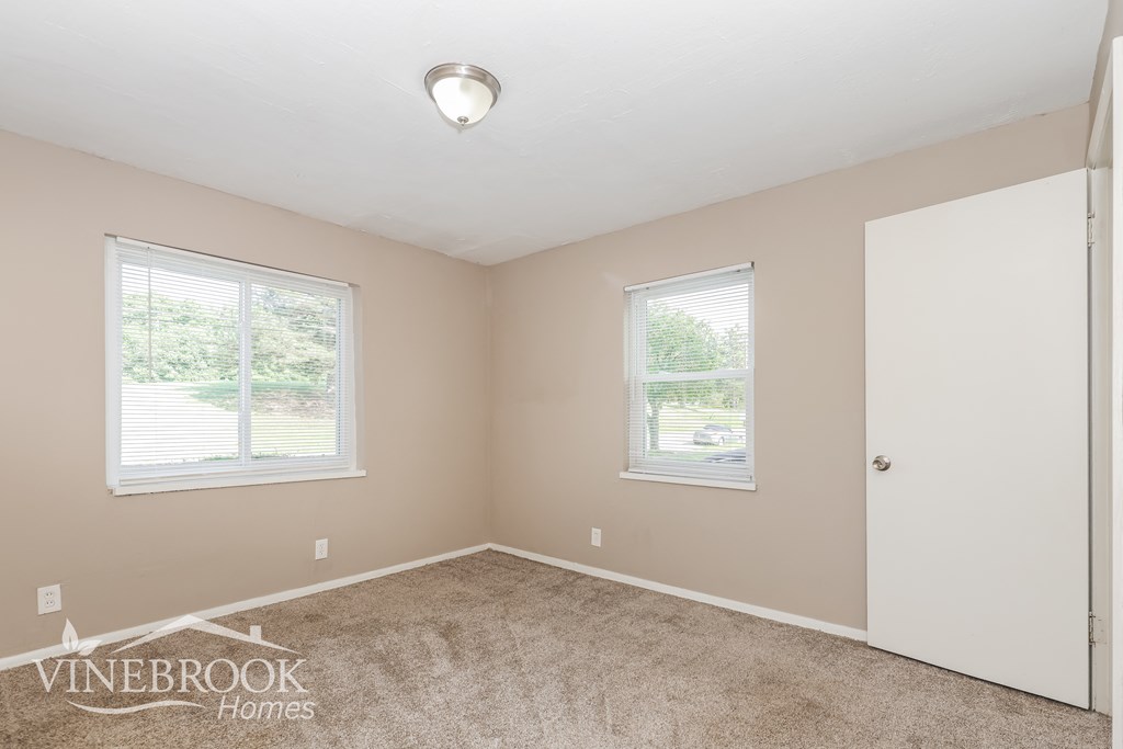 a bedroom with a carpeted floor and two windows