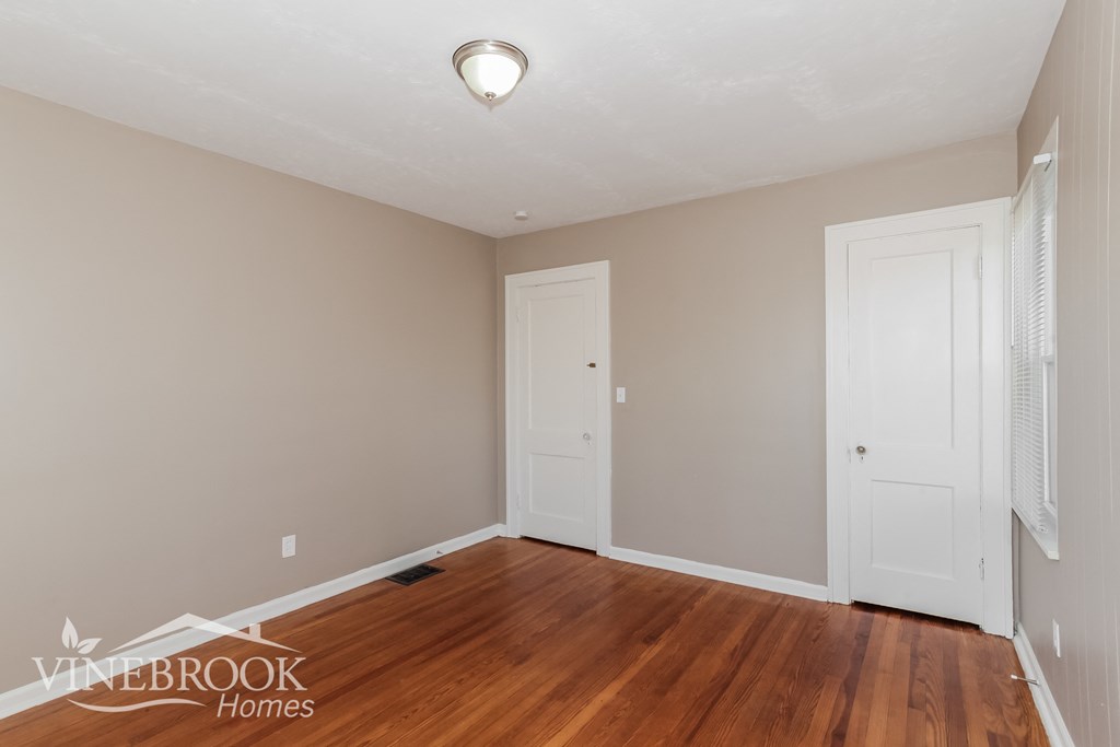 a bedroom with a hard wood floor and two doors