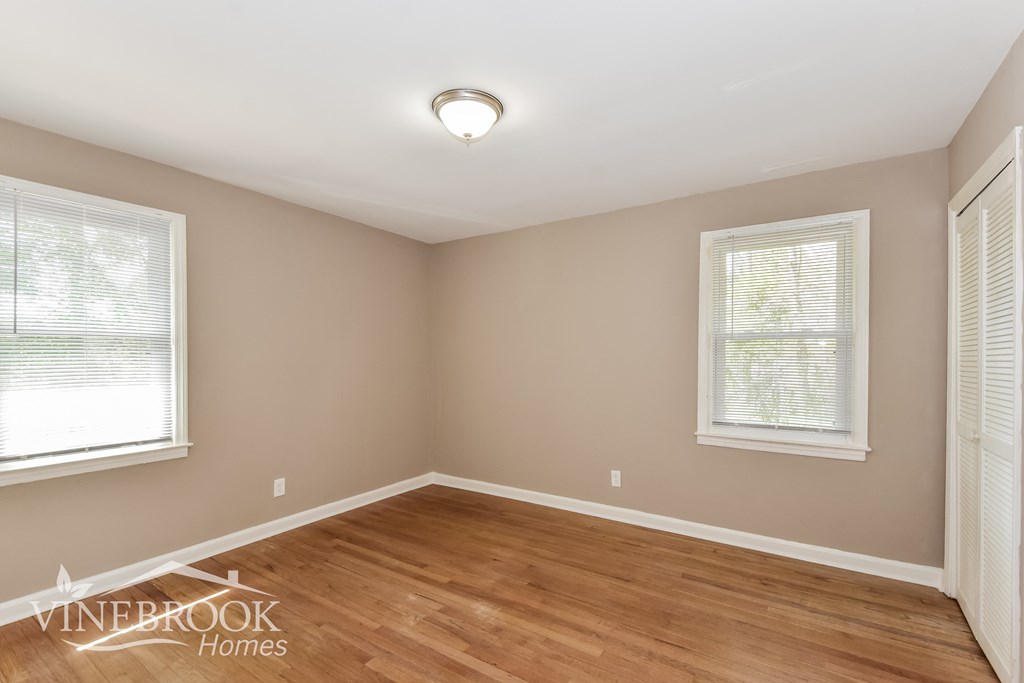 the second bedroom after renovation with wood flooring and two windows