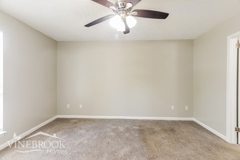 a living room with a ceiling fan and a carpet