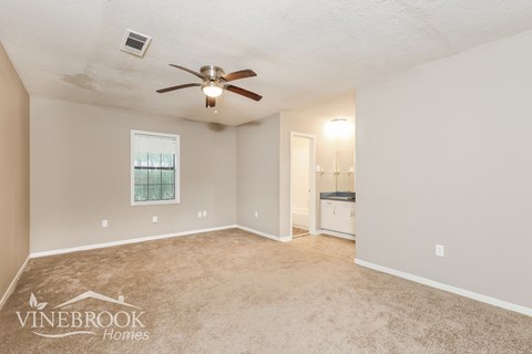 a living room with carpet and a ceiling fan