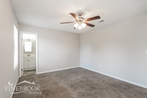 a living room with a ceiling fan and a carpet