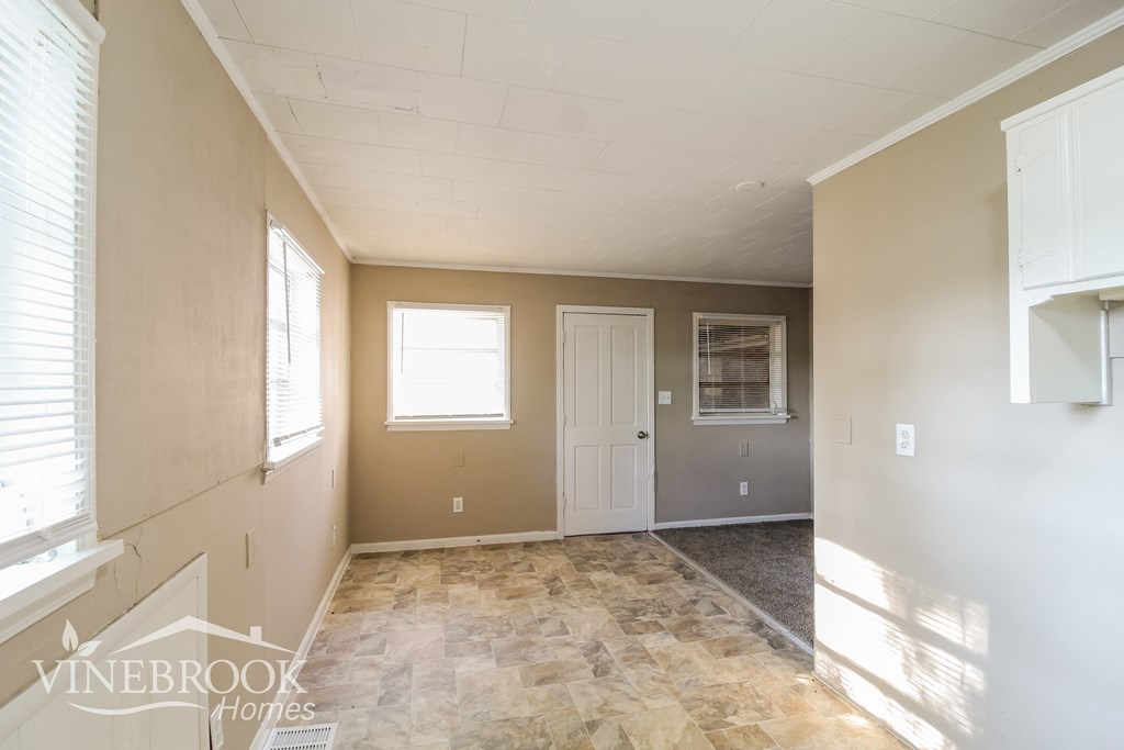 an empty living room with a white door and a window