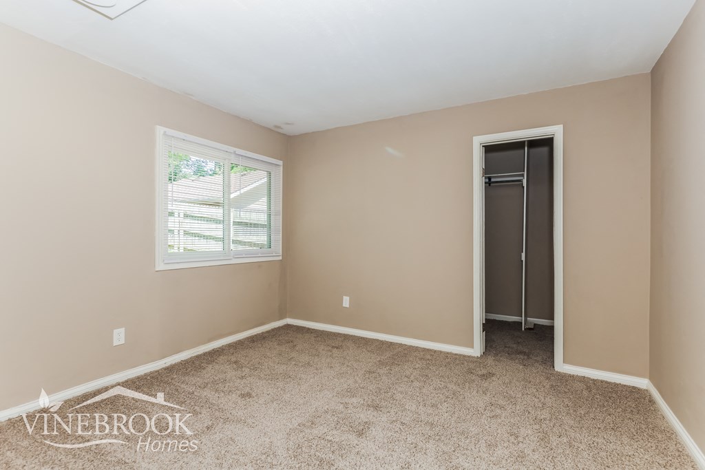 a bedroom with carpet and a door to a closet