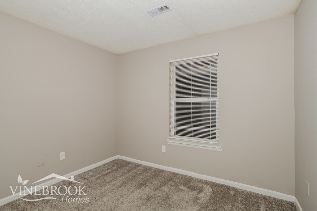 the upstairs bedroom has a carpeted floor and a window