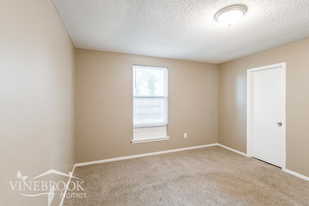 a bedroom with a carpeted floor and a window