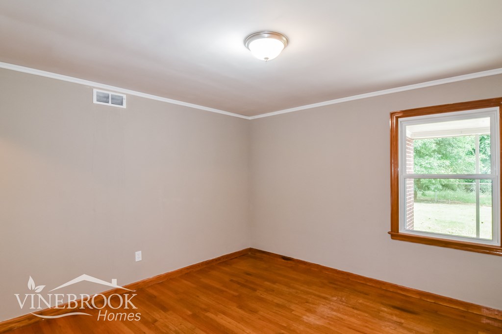 the living room of a house with wood floors and a window