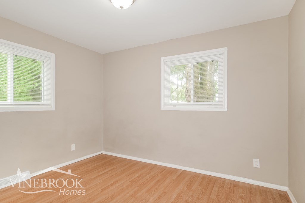 the living room of a home with wood flooring and two windows