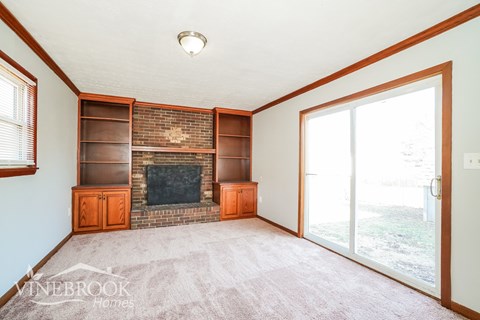 A living room with a fireplace and a carpet on the floor.