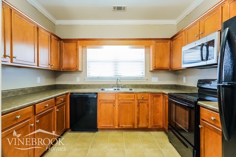 A kitchen with wooden cabinets and black appliances.