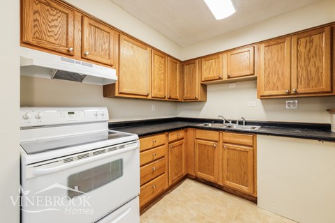 A kitchen with wooden cabinets and a white stove top oven.