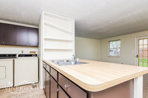 A kitchen with a sink and a wooden counter top.