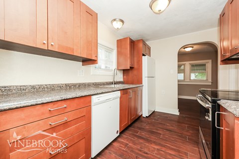 A kitchen with wooden cabinets and a Vinebrook Homes logo.