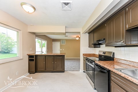 A kitchen with brown cabinets and a black dishwasher.