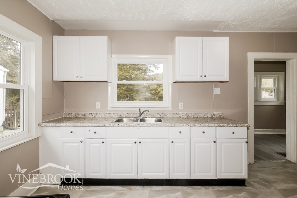 A kitchen with white cabinets and a granite countertop.