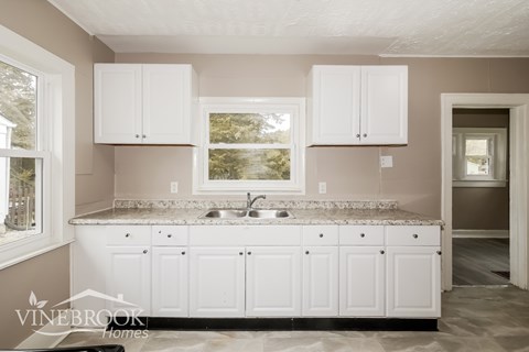 A kitchen with white cabinets and a granite countertop.