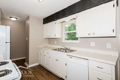 A kitchen with white cabinets and a window.