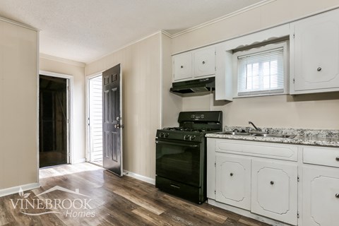 A kitchen with a black oven and white cabinets.