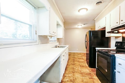 A kitchen with a black refrigerator and a white counter.