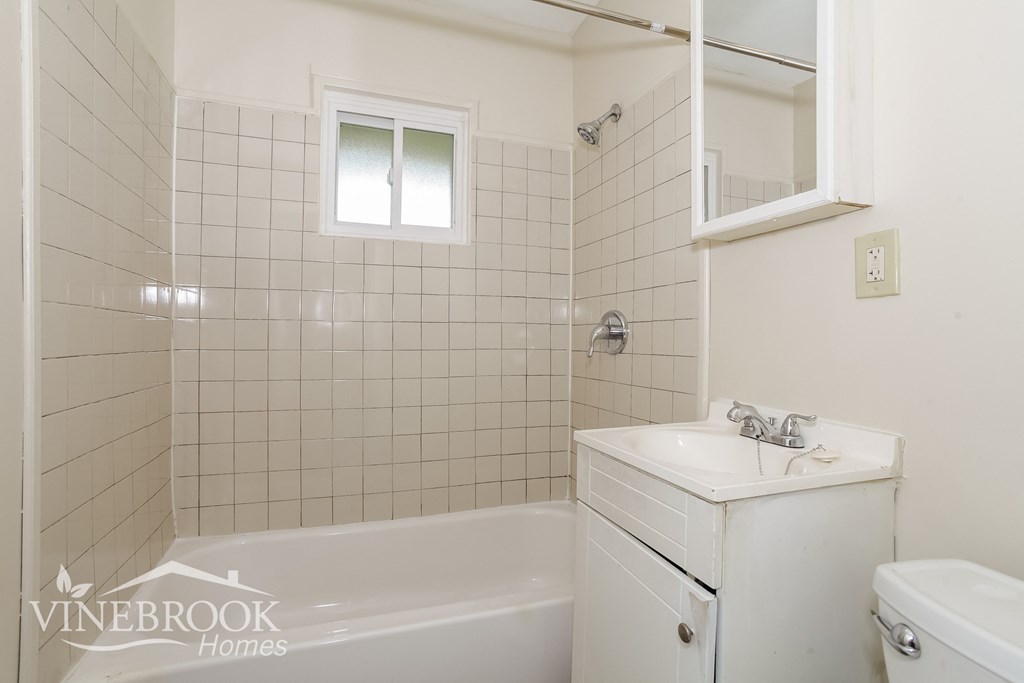 a white bathroom with a tub and a sink and a mirror