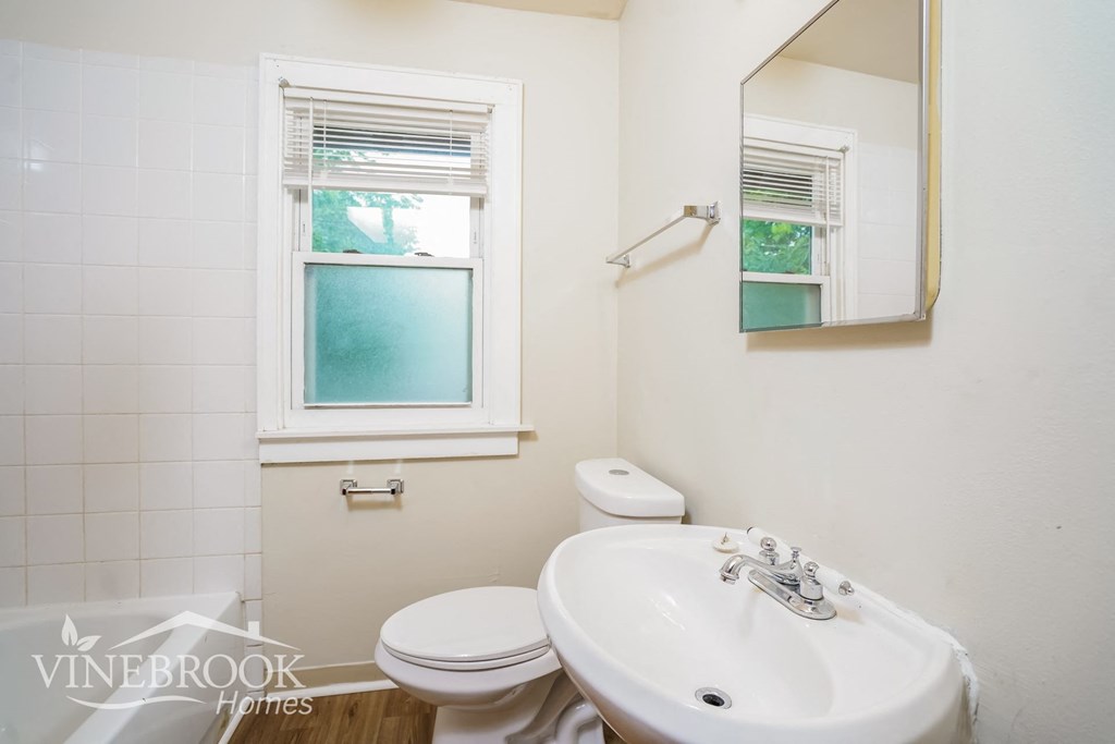 a white bathroom with a sink toilet and a mirror