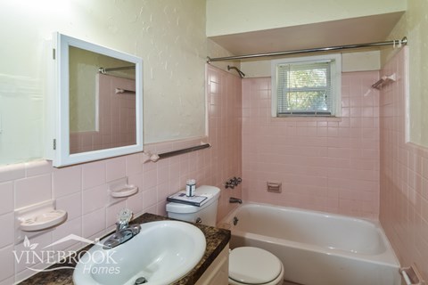 A bathroom with pink tiles and a white toilet.