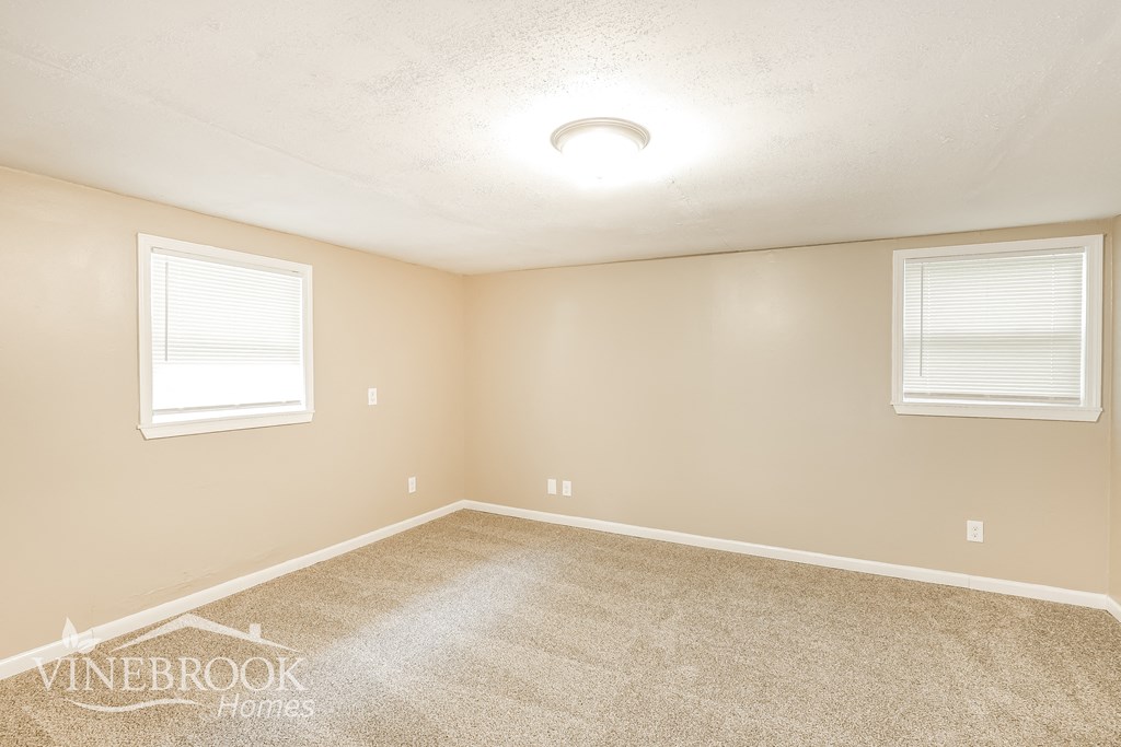 a empty room with carpet and two windows