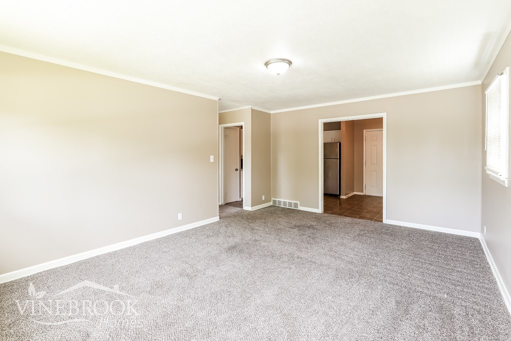 a spacious living room with carpet and white walls