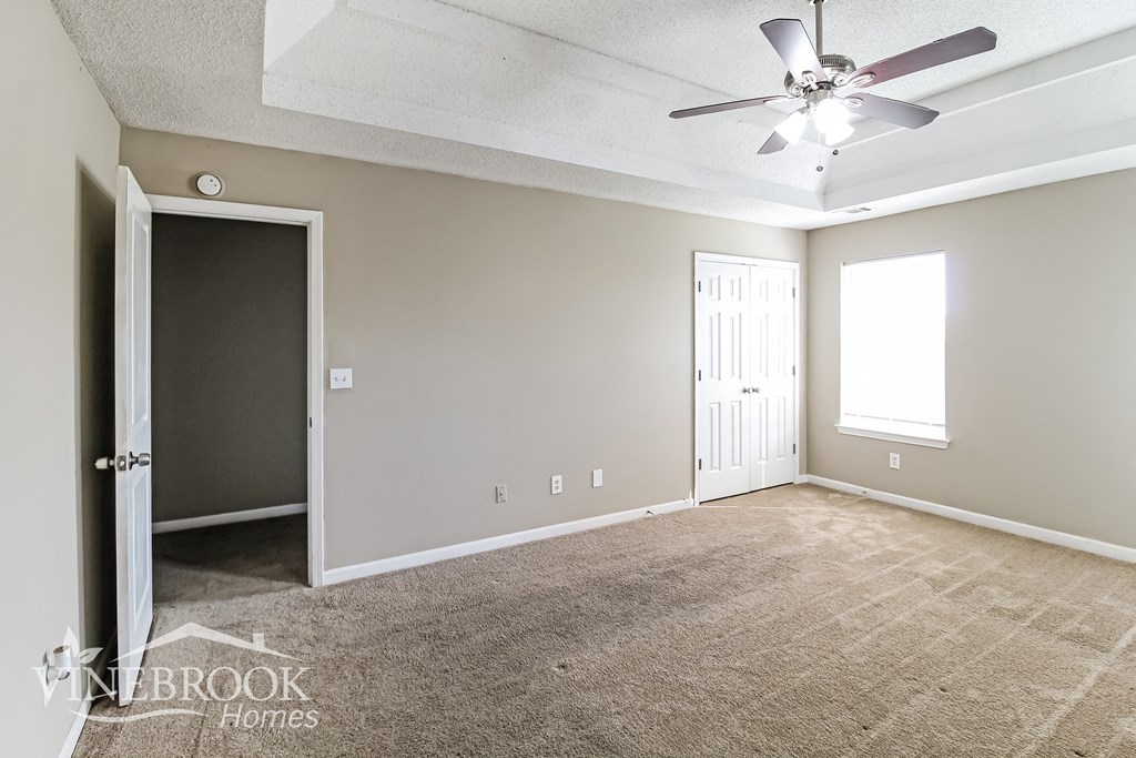 an empty living room with a ceiling fan and a door to a closet