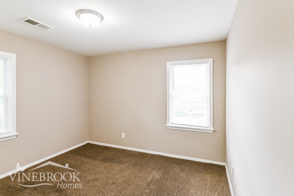 a bedroom with a carpeted floor and two windows