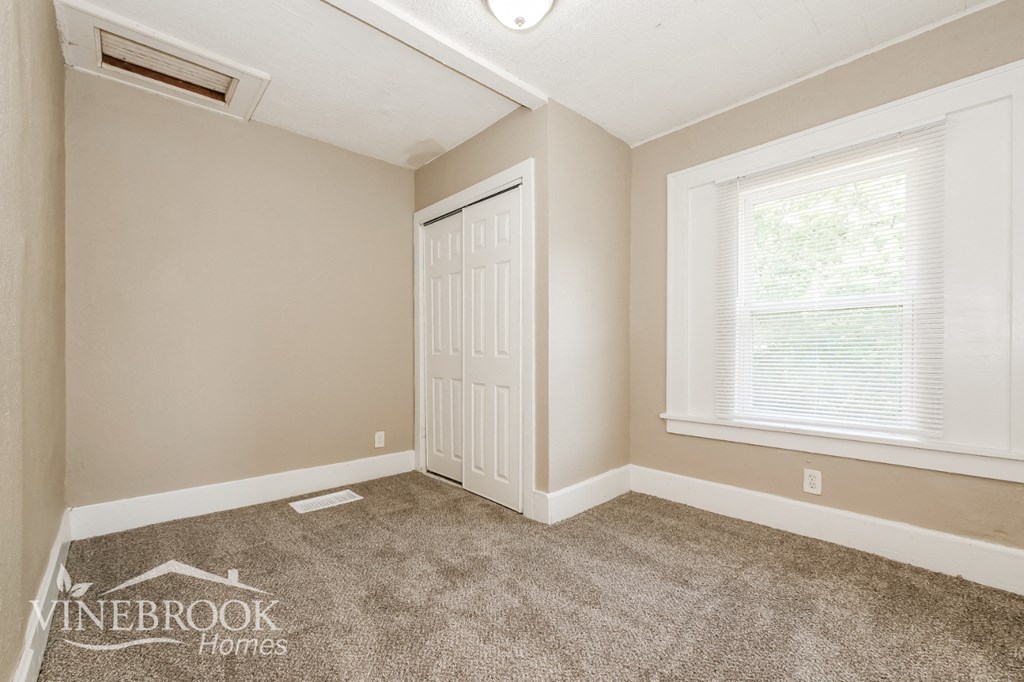 the bedroom of a home with a carpeted floor and a white door and window