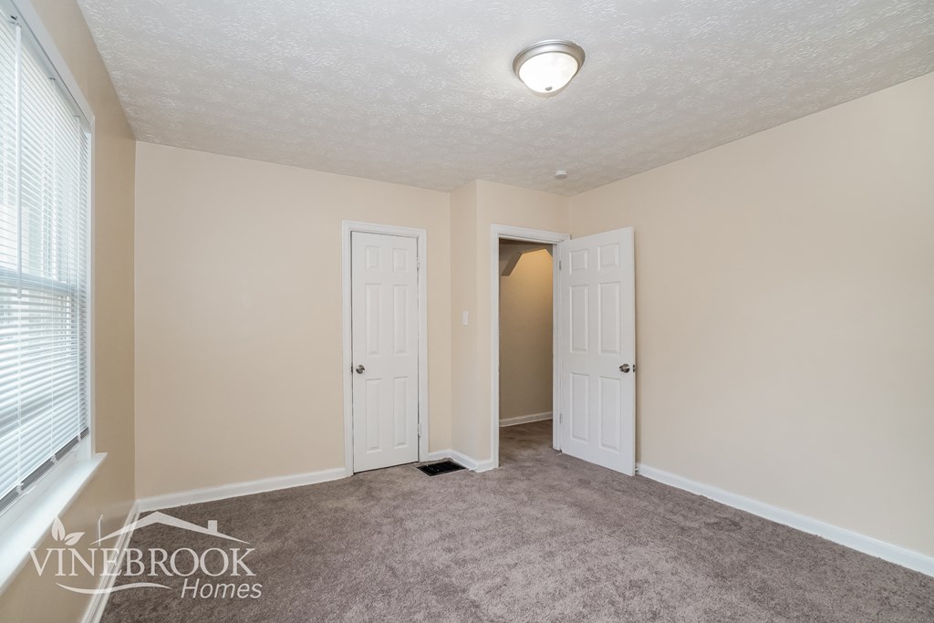 a living room with a carpeted floor and a door to a closet