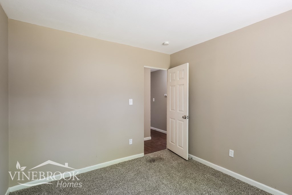 a bedroom with a white door and a carpeted floor