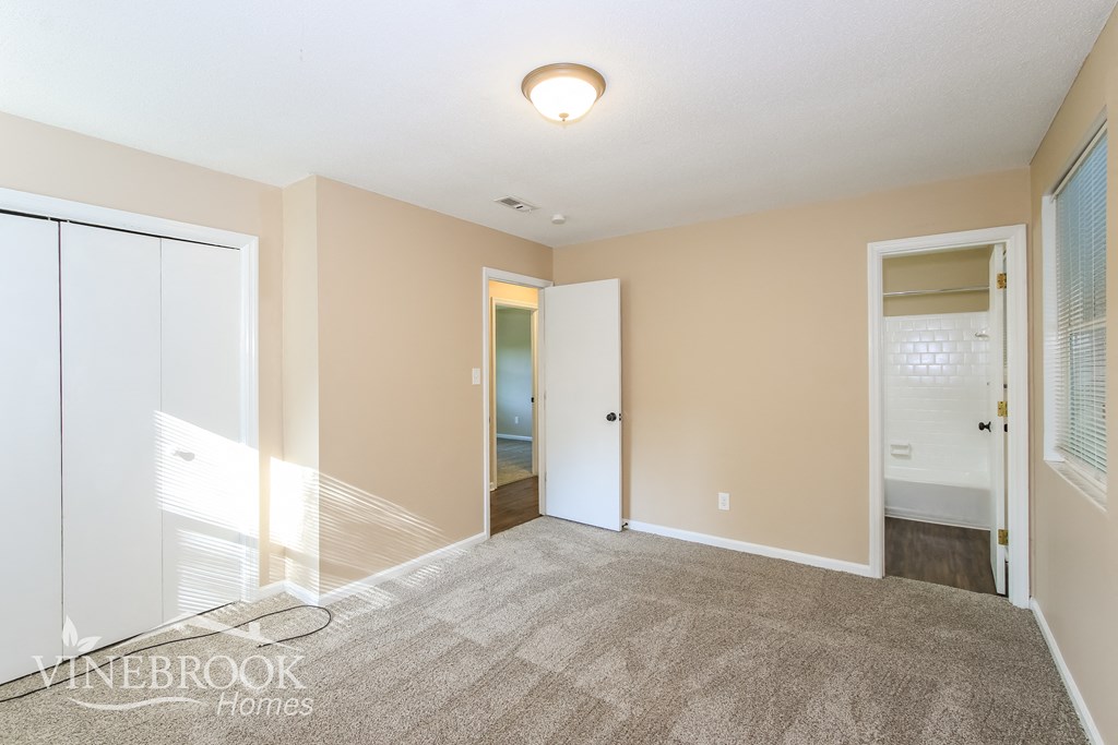 a bedroom with a carpeted floor and a door to a bathroom