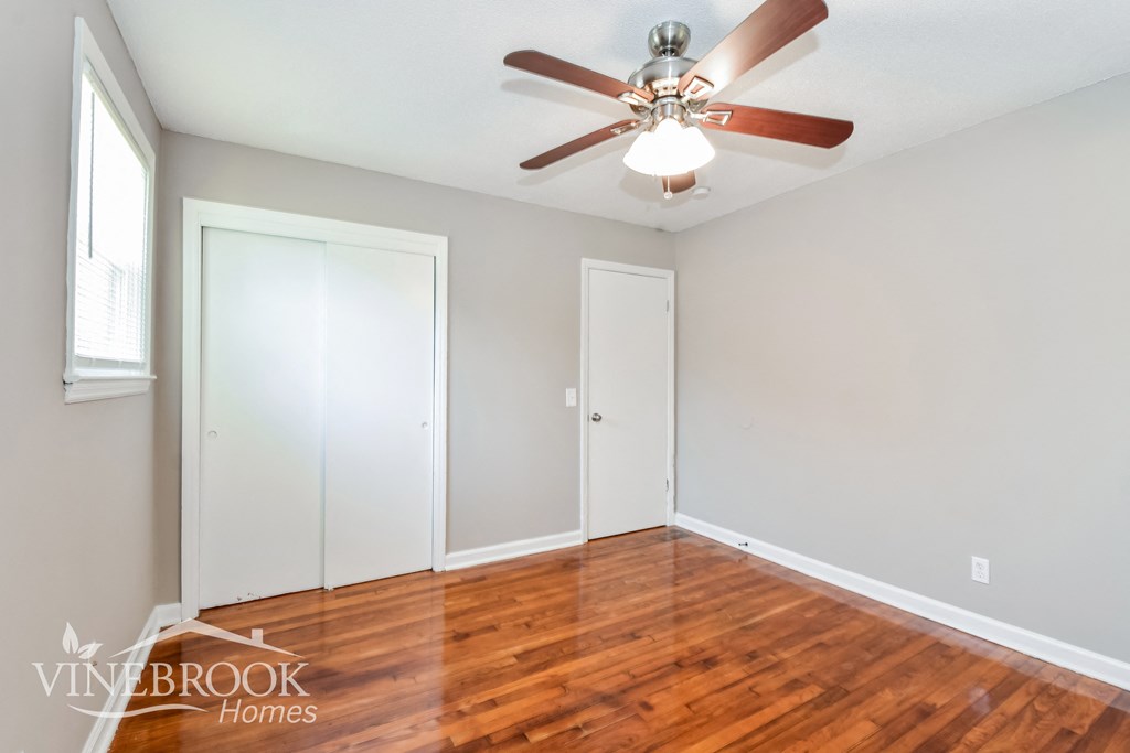 a living room with wood floors and a ceiling fan