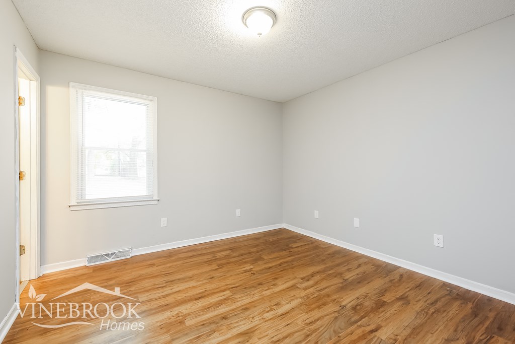 the living room of a home with wood flooring and a window
