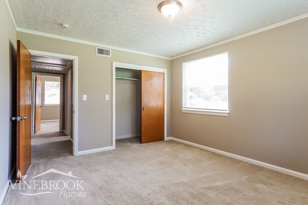 a bedroom with a carpeted floor and a door to a closet and a hallway