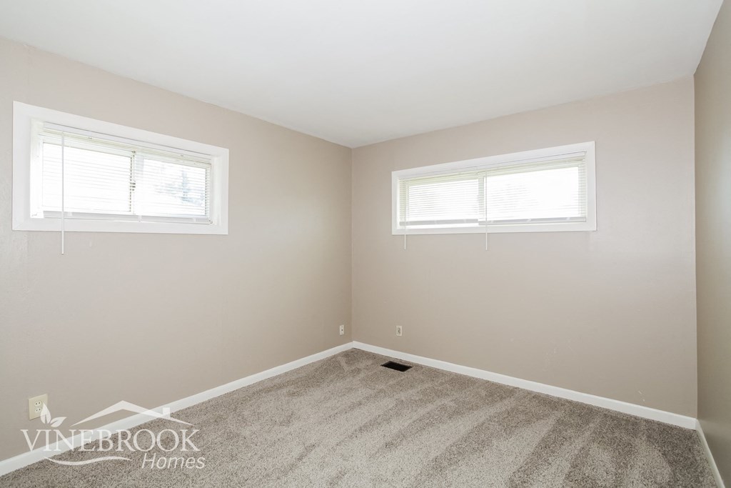 a bedroom with a carpeted floor and two windows