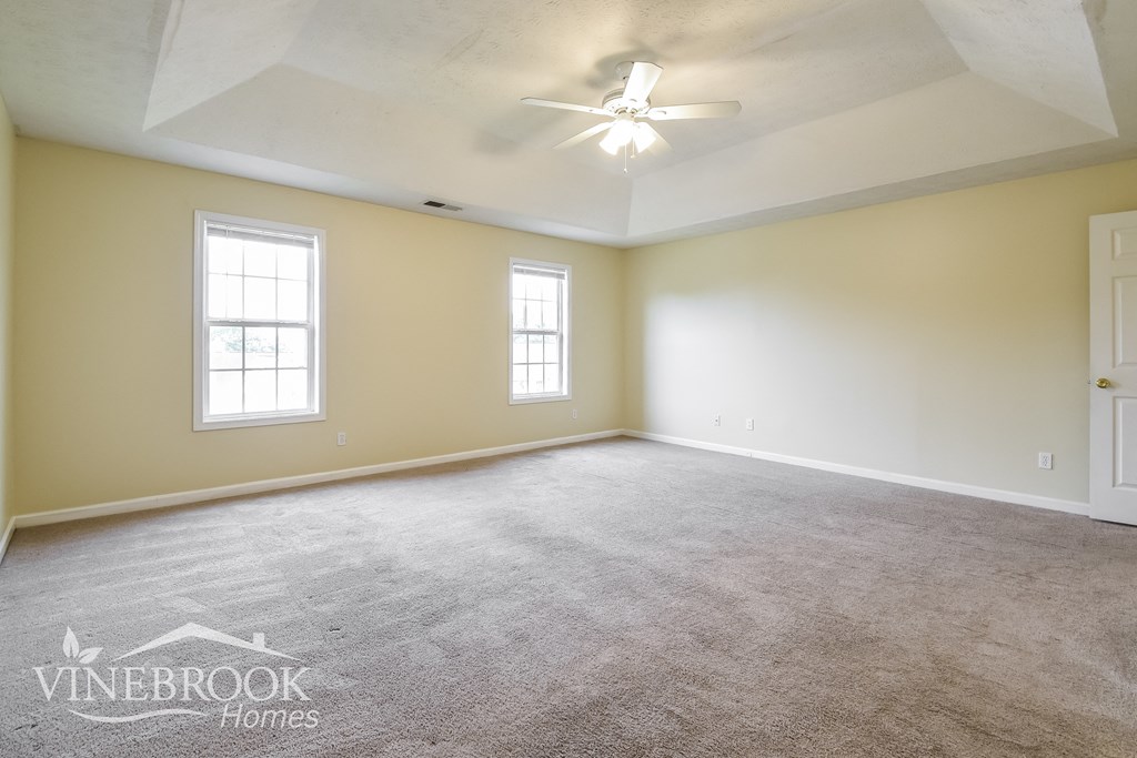 the living room of a new home with carpet and a ceiling fan