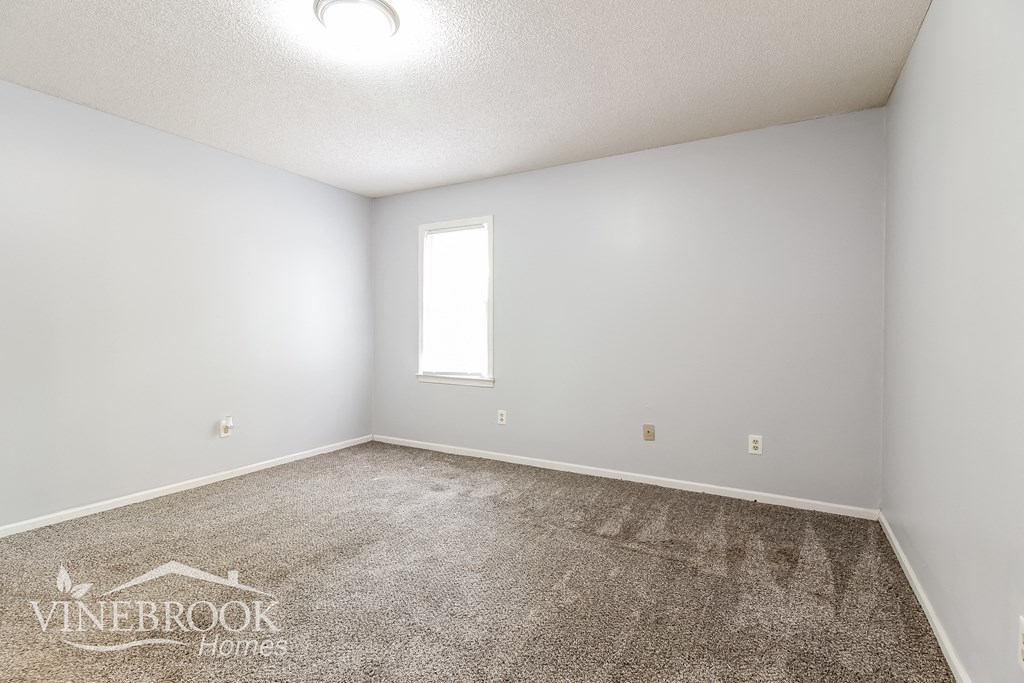 the spacious living room with carpeting and a window